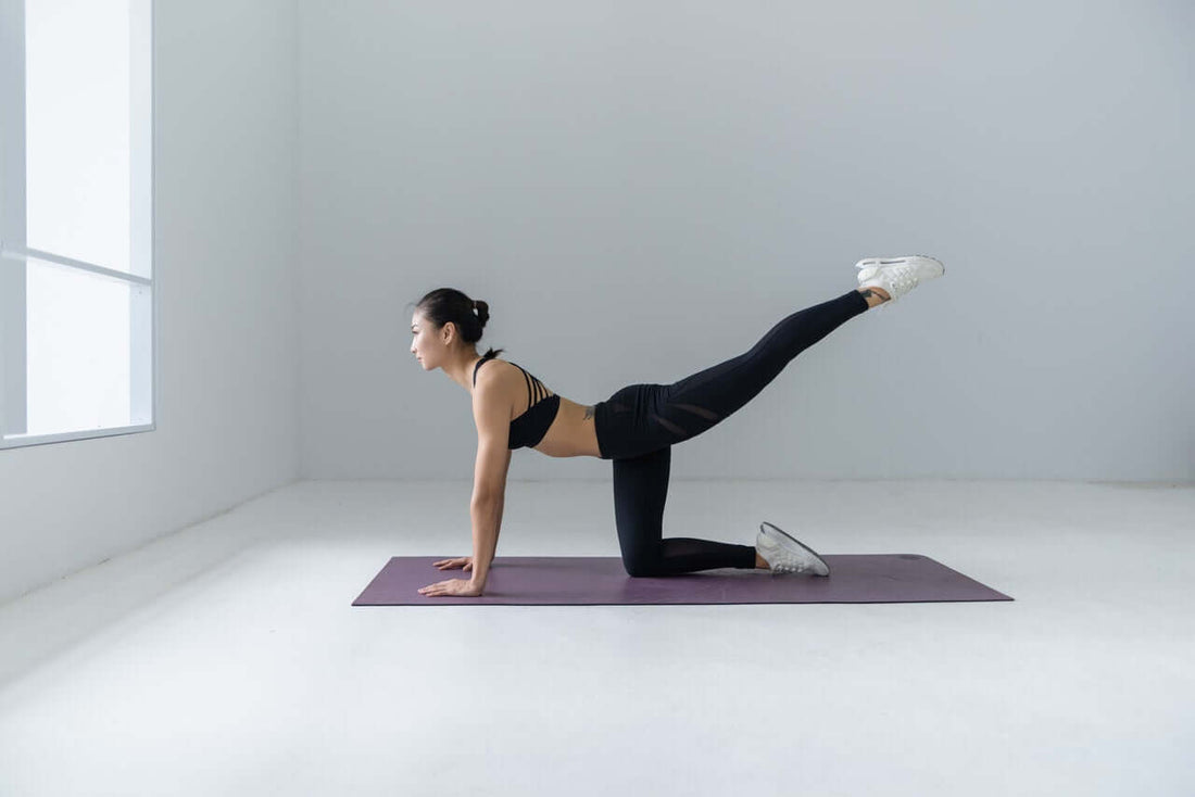 Woman on hands and knees on a purple mat performing a bird dog exercise