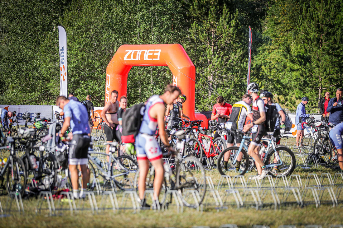 Cyclists gather near an orange Zone3 arch at a race start area.