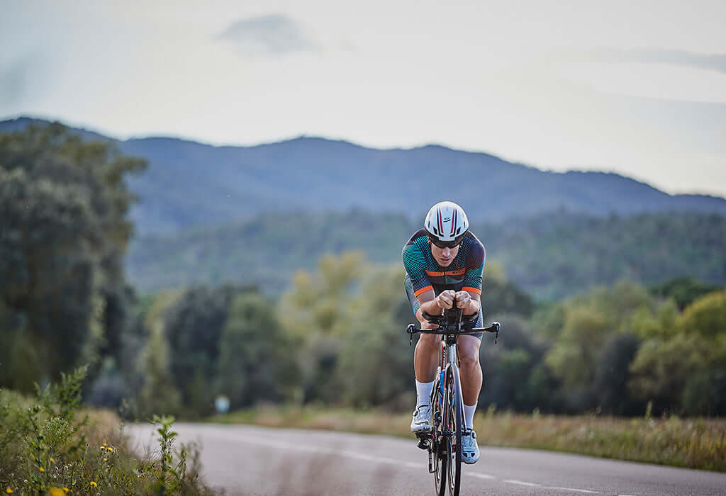 Cyclist in aero position on a country road with hills in the distance