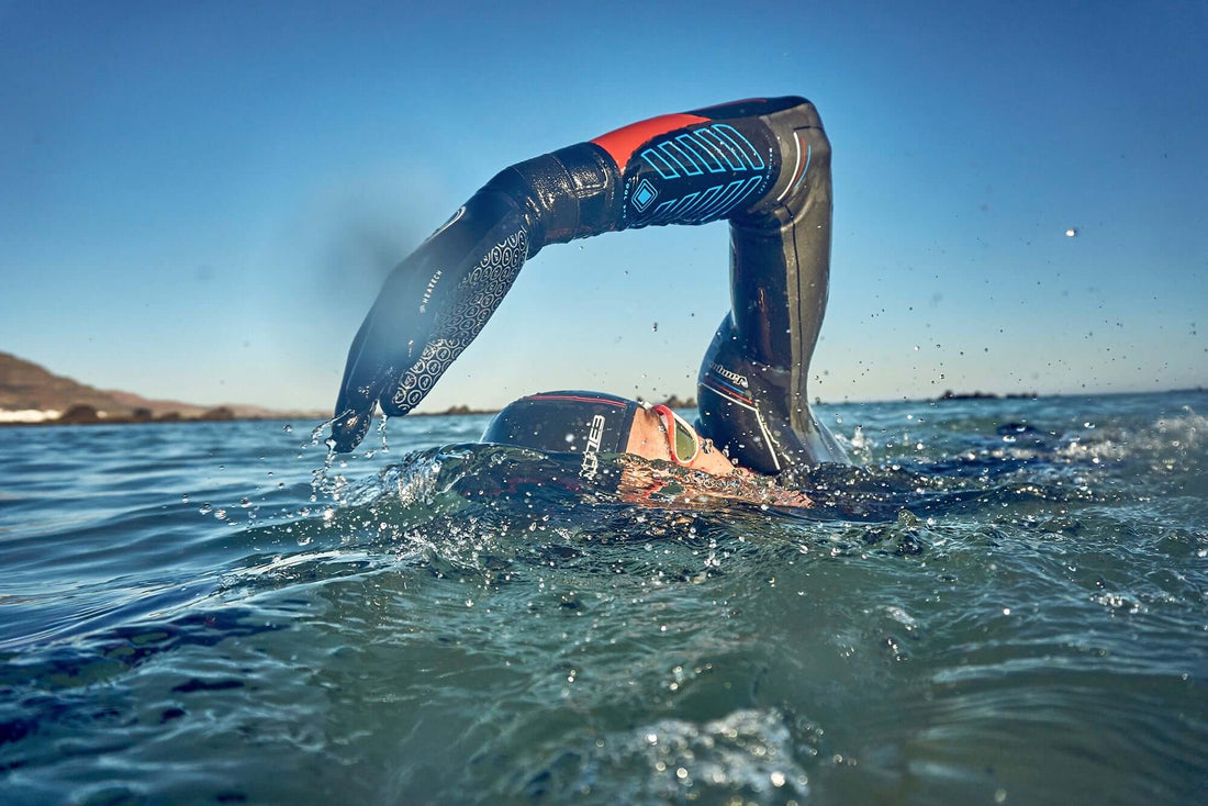 Open water swimmer wearing a black Zone3 wetsuit with blue patterned neoprene sleeves