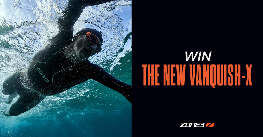 Underwater shot of a swimmer in a black Zone3 wetsuit with orange goggles slicing through blue water