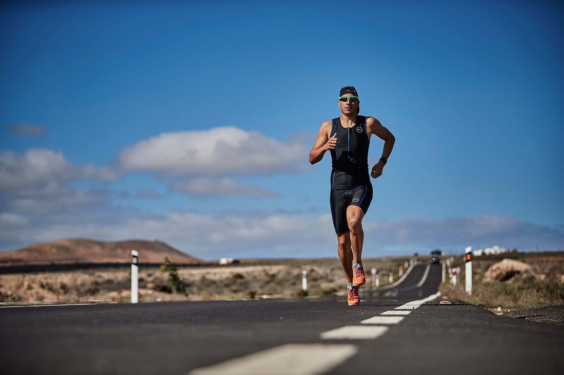 Triathlete running on an open road under a clear blue sky