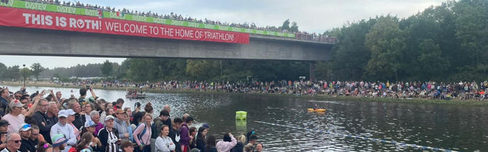 a photo of the iconic Main-Donau- Canal at Challenge Roth, with crowds of people gathered at the swim exit of the triathlon. zone3 signs line the exit.