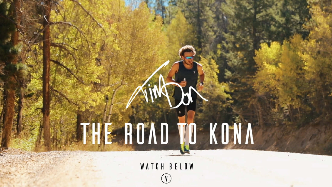 Male runner in a black sleeveless top and sunglasses runs along a sunlit forest road.