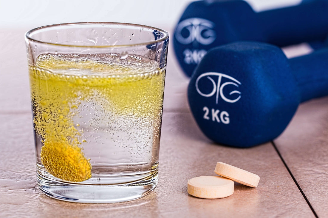 Glass of sparkling lemon water on a wooden table with a blue 2 kg dumbbell in the background