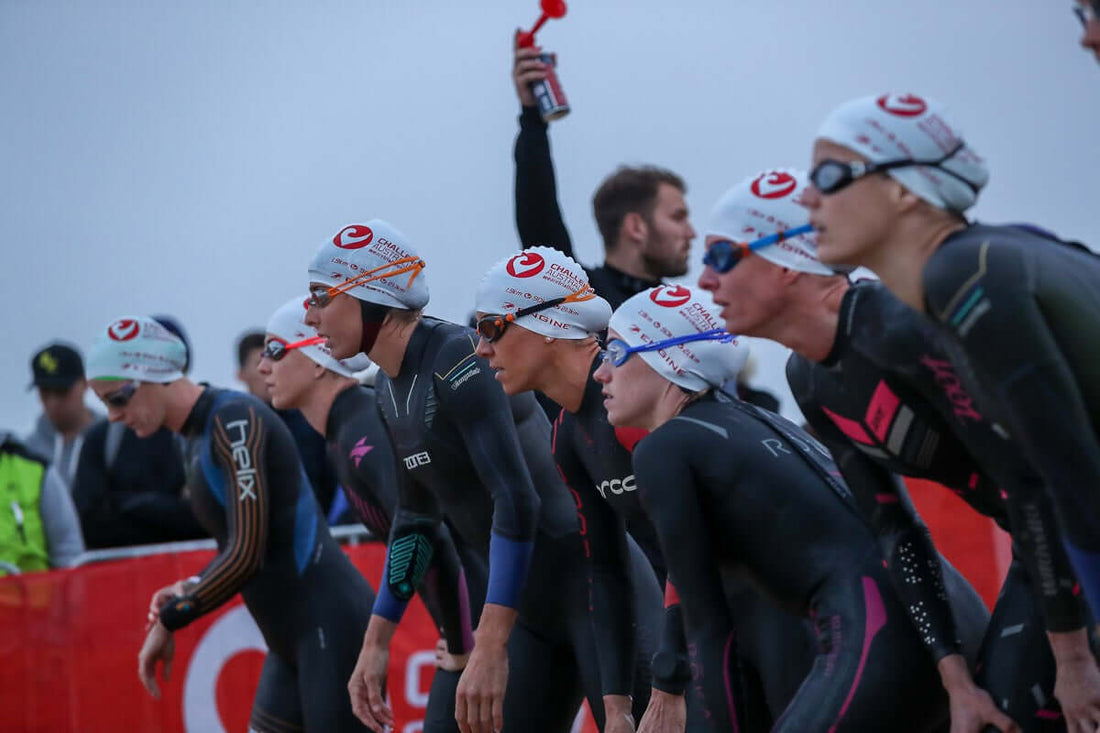 Triathletes in wetsuits and white swim caps riding in a peloton at Challenge Melbourne