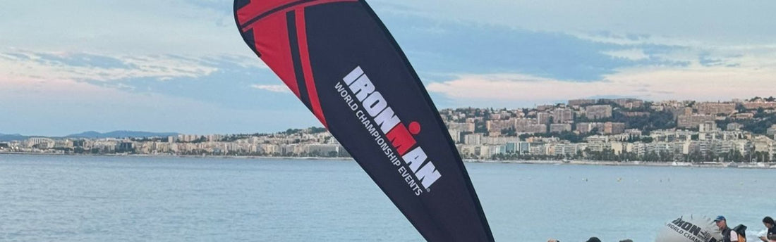 a flag with the Ironman Triathlon logo and words world championship on it, against a backdrop of ocean