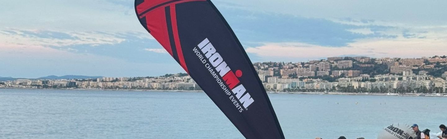 a flag with the Ironman Triathlon logo and words world championship on it, against a backdrop of ocean