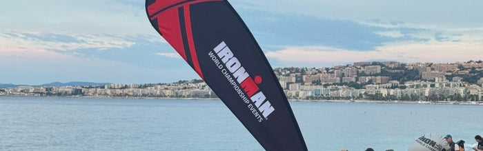 a flag with the Ironman Triathlon logo and words world championship on it, against a backdrop of ocean