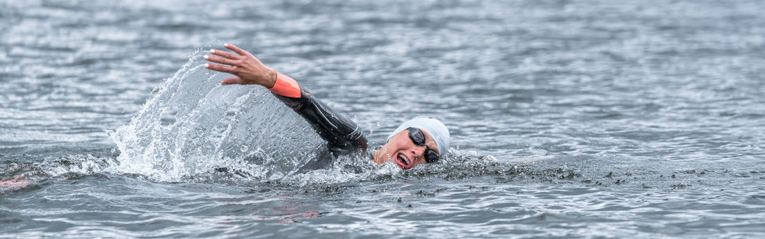 Rachel Klamer is swimming in the open water wearing a wetsuit, goggles and swim cap