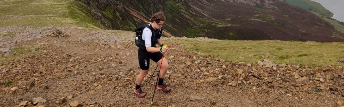 Sarah Kelly, ZONE3 Ambassador, is running up hill in the Lake Dsitrict with running poles