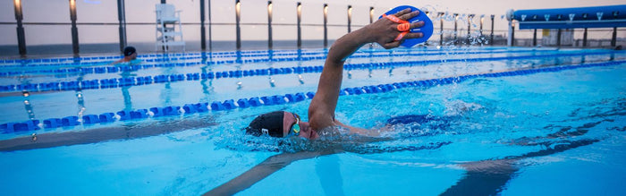 a man is swimming in a pool and is doing front crawl using zone3 hand paddles
