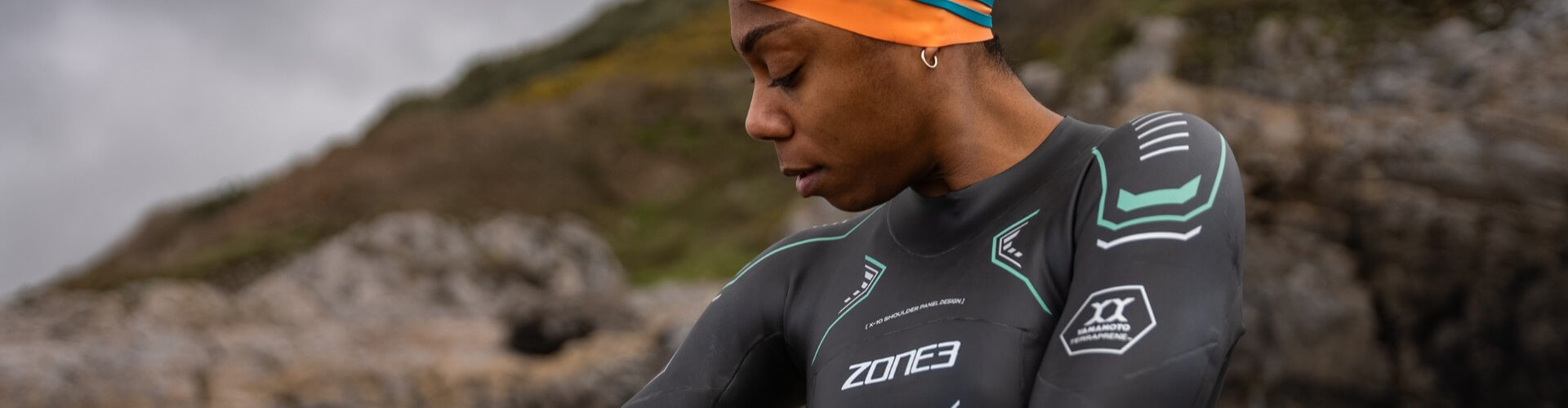 A swimmer prepares to enter the water in a sleek B-Prene Wetsuit, showcasing high-performance design and eco-friendly features.