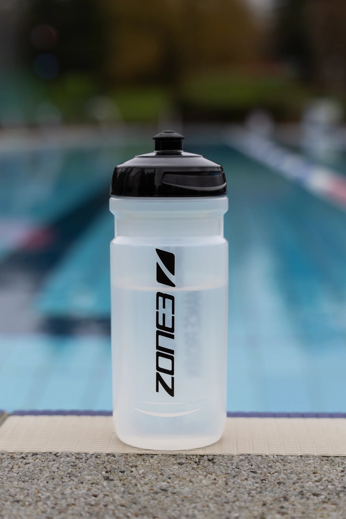 Zone3 transparent water bottle with black detailing. blurred pool background. 