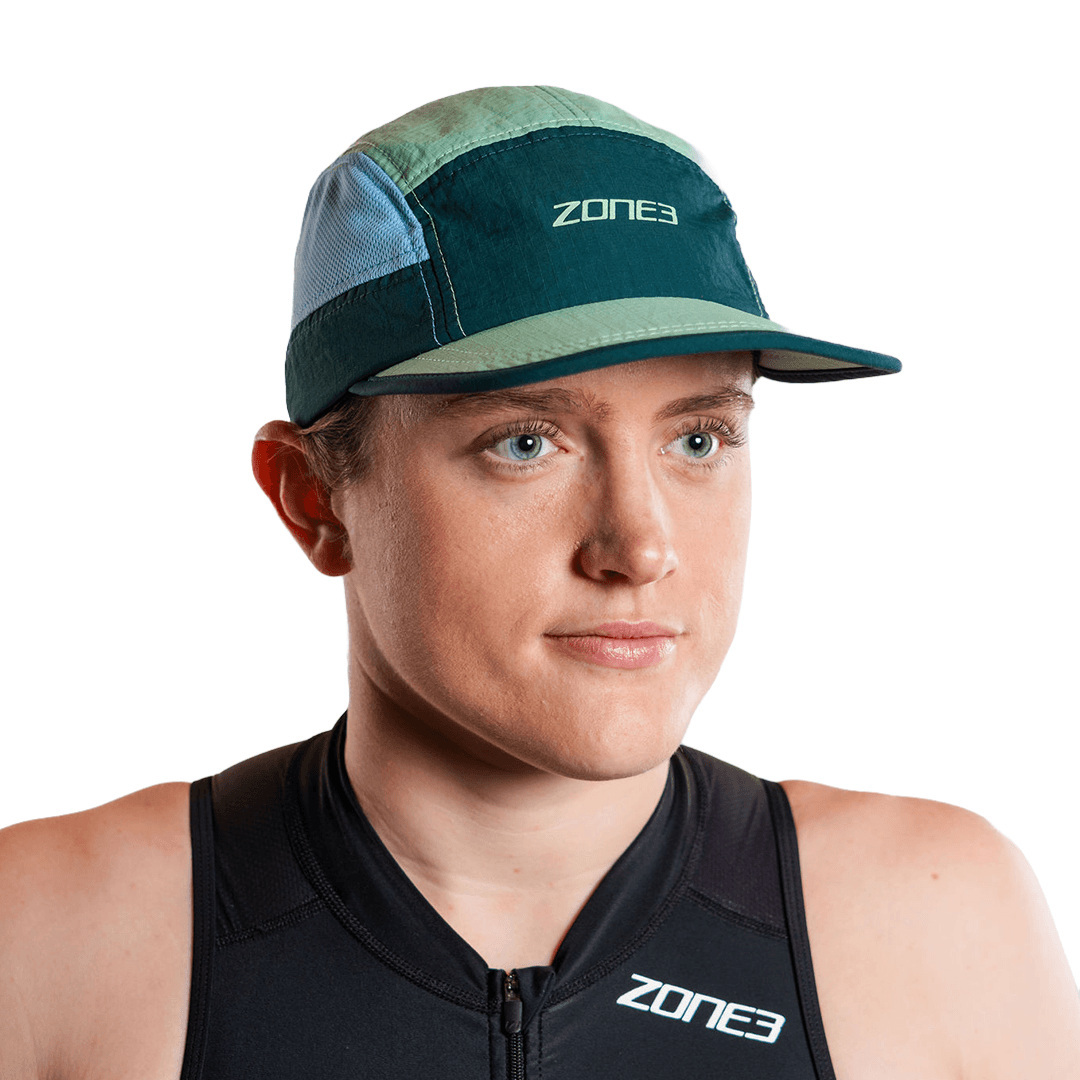 Person, die eine blaugrüne 5-Panel-Laufkappe mit Zone3-Logo auf weißem Hintergrund trägt