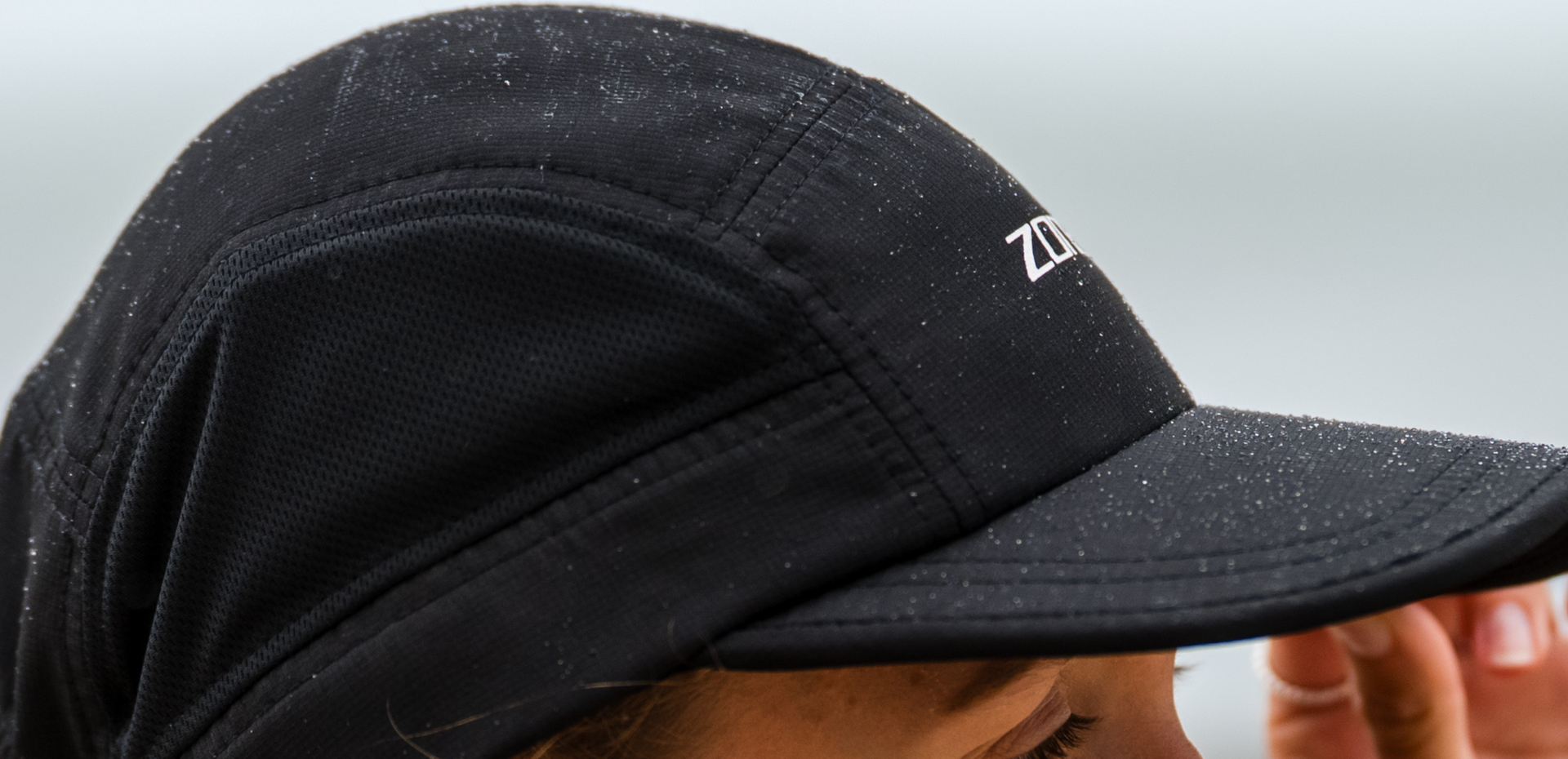 Black 5 panel running cap with zone3 logo on a blurred background