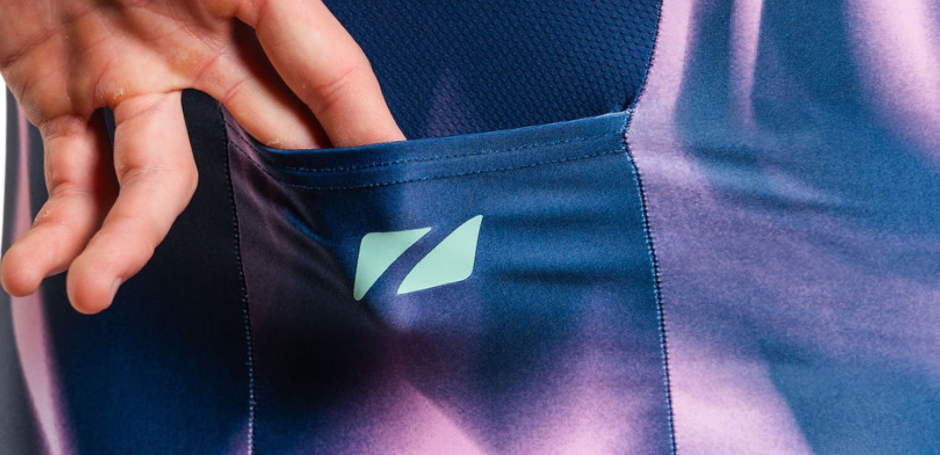 Person wearing purple and pink zone3 trisuit with 'Zone3' branding demonstrating the back pockets 