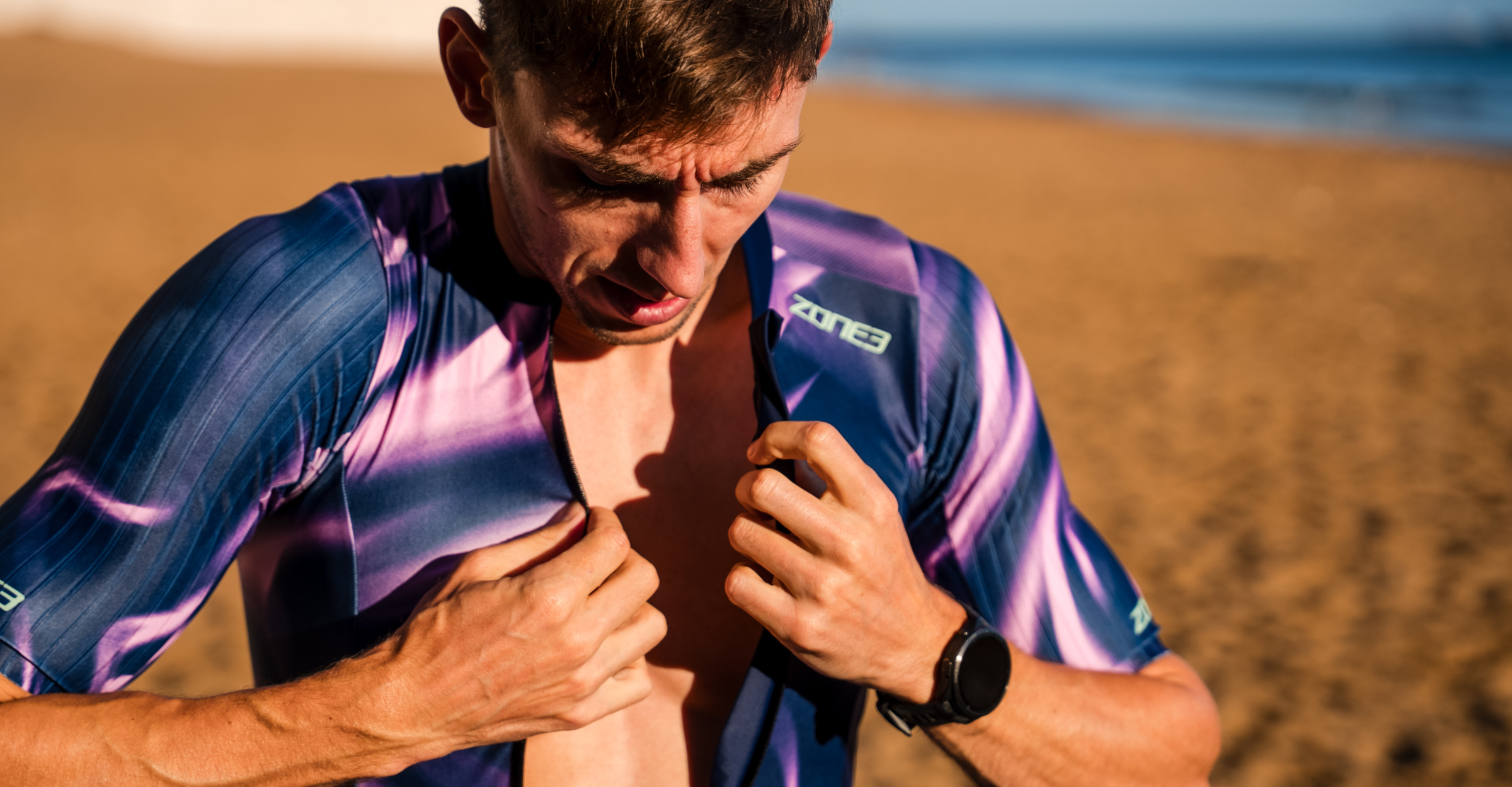 Cyclist in a pink and purple zone3 trisuit with the beach and sea in the background