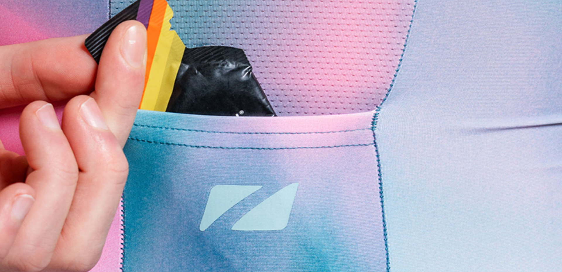 Person wearing teal and pink zone3 trisuit with 'Zone3' branding demonstrating the back pockets 