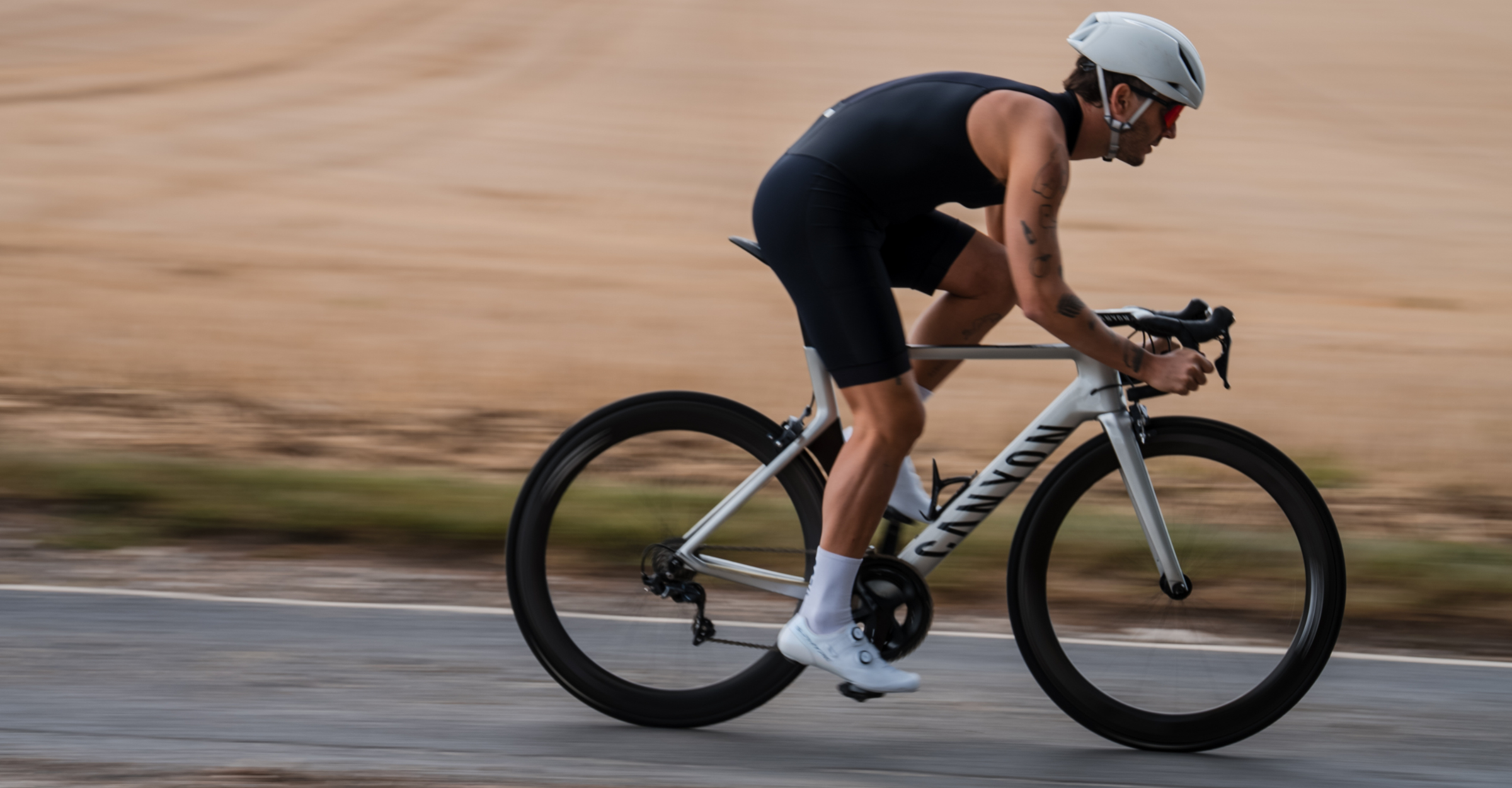 Person cycling wearing zone3 black activate+ sleeveless trisuit on a blurred background