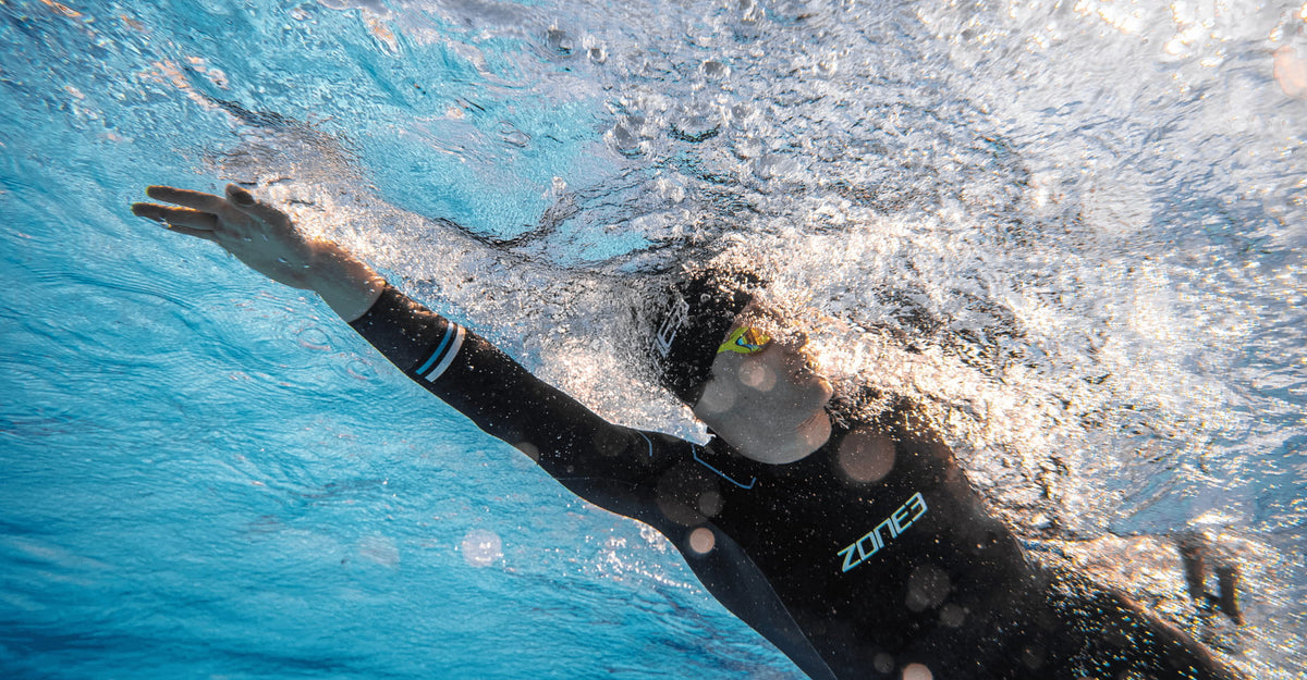 Athlete swimming in the pool wearing the Zone3 Advance wetsuit. black with blue detailing. 