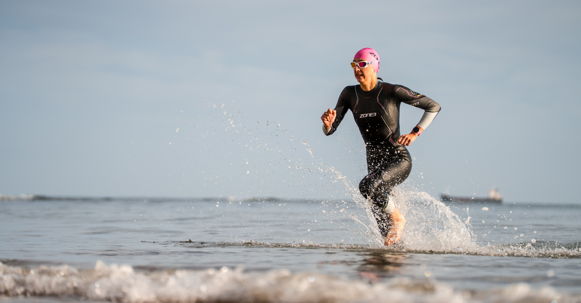 Person running out of the water on a beach with a clear sky