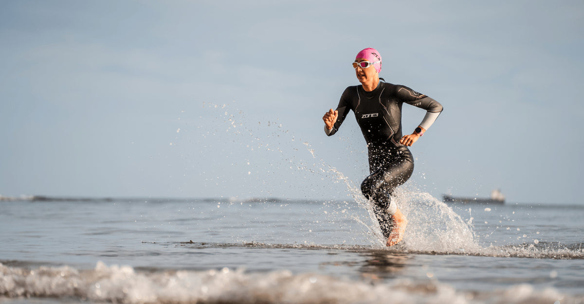 Athlete running out of the water in a Zone3 Aspire wetsuit. 