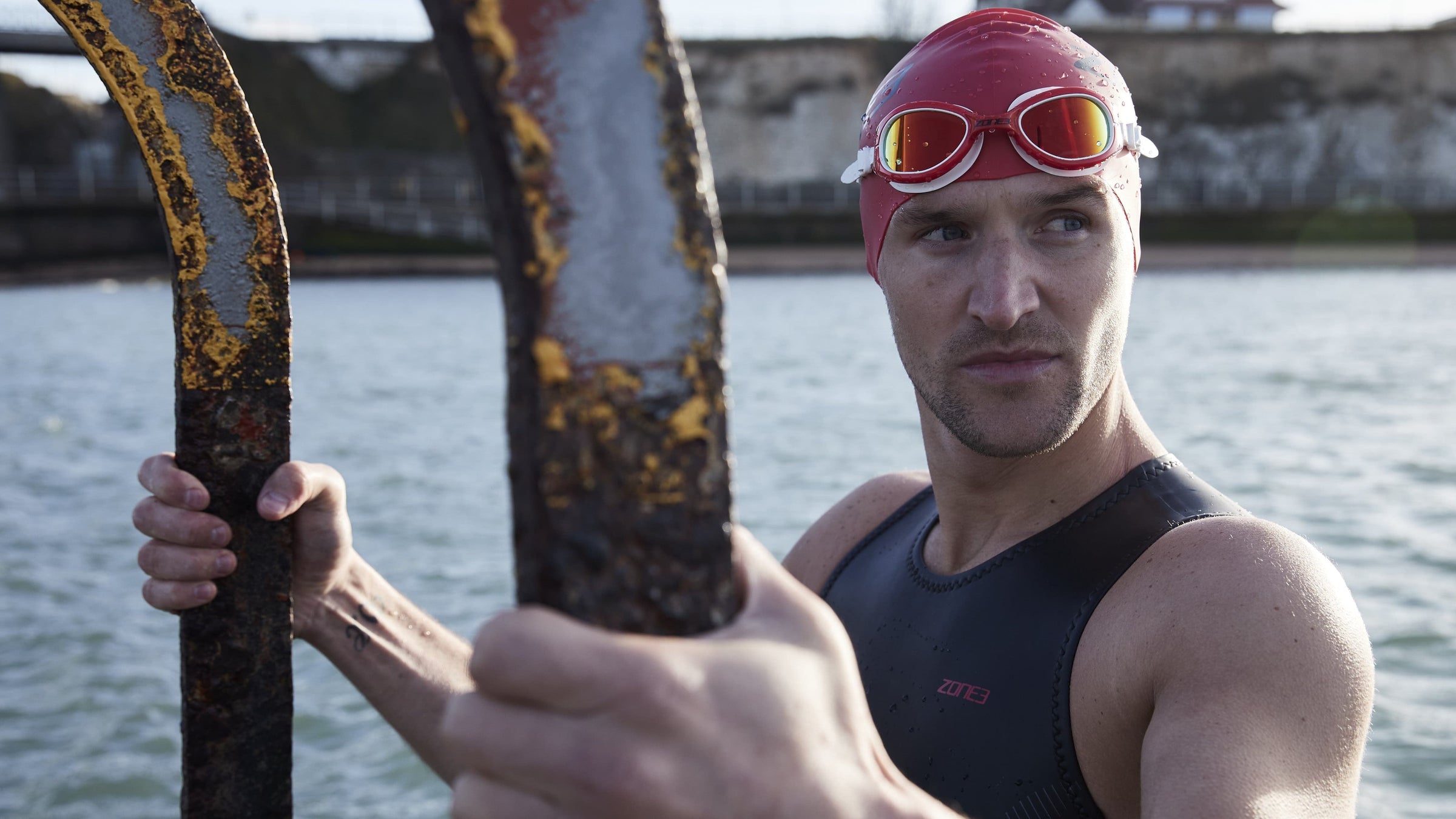 Athlete getting out of open water wearing Zone3 gear and the red attack goggles 