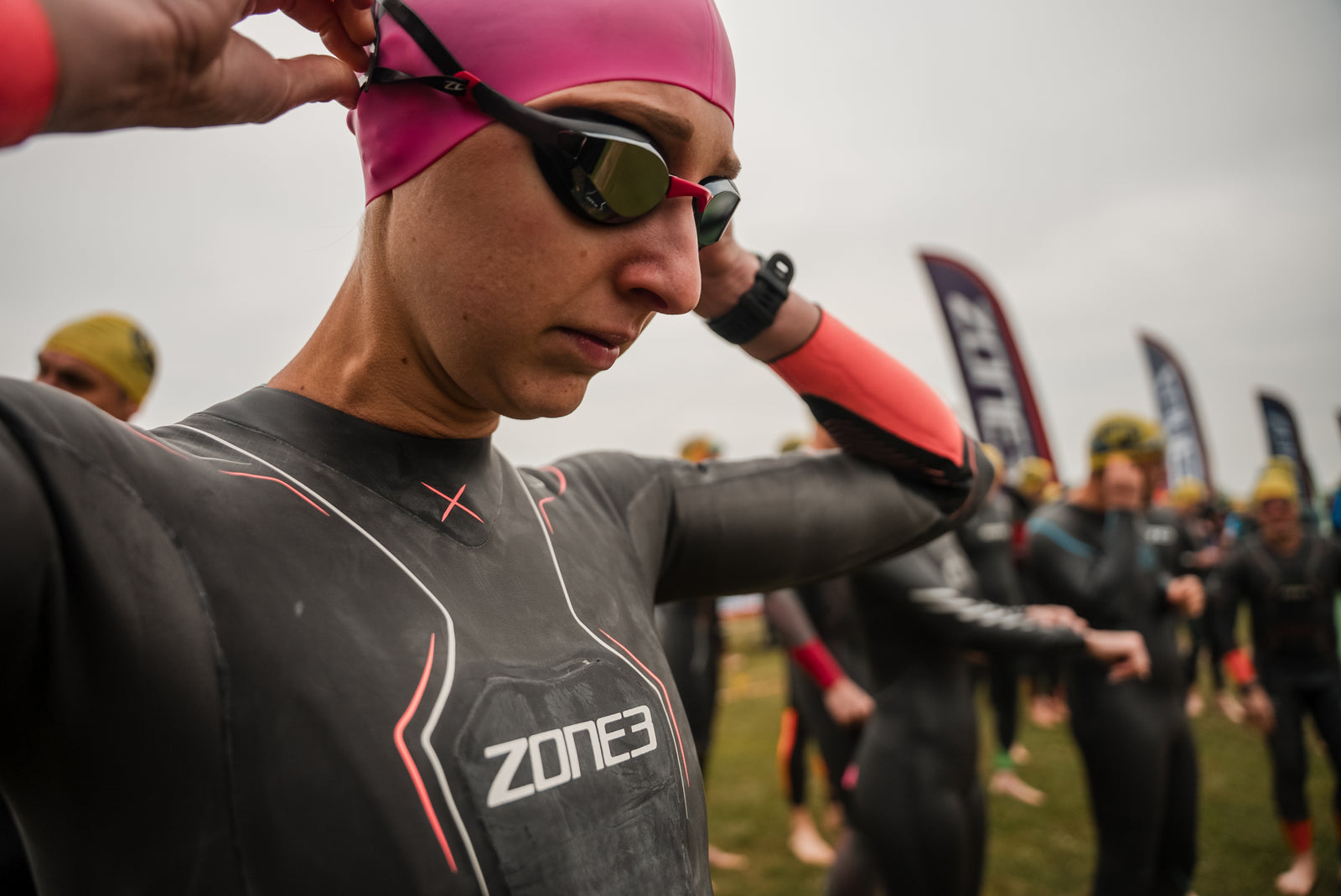 Women wearing Black goggles and wetsuit with a pink swim cap 