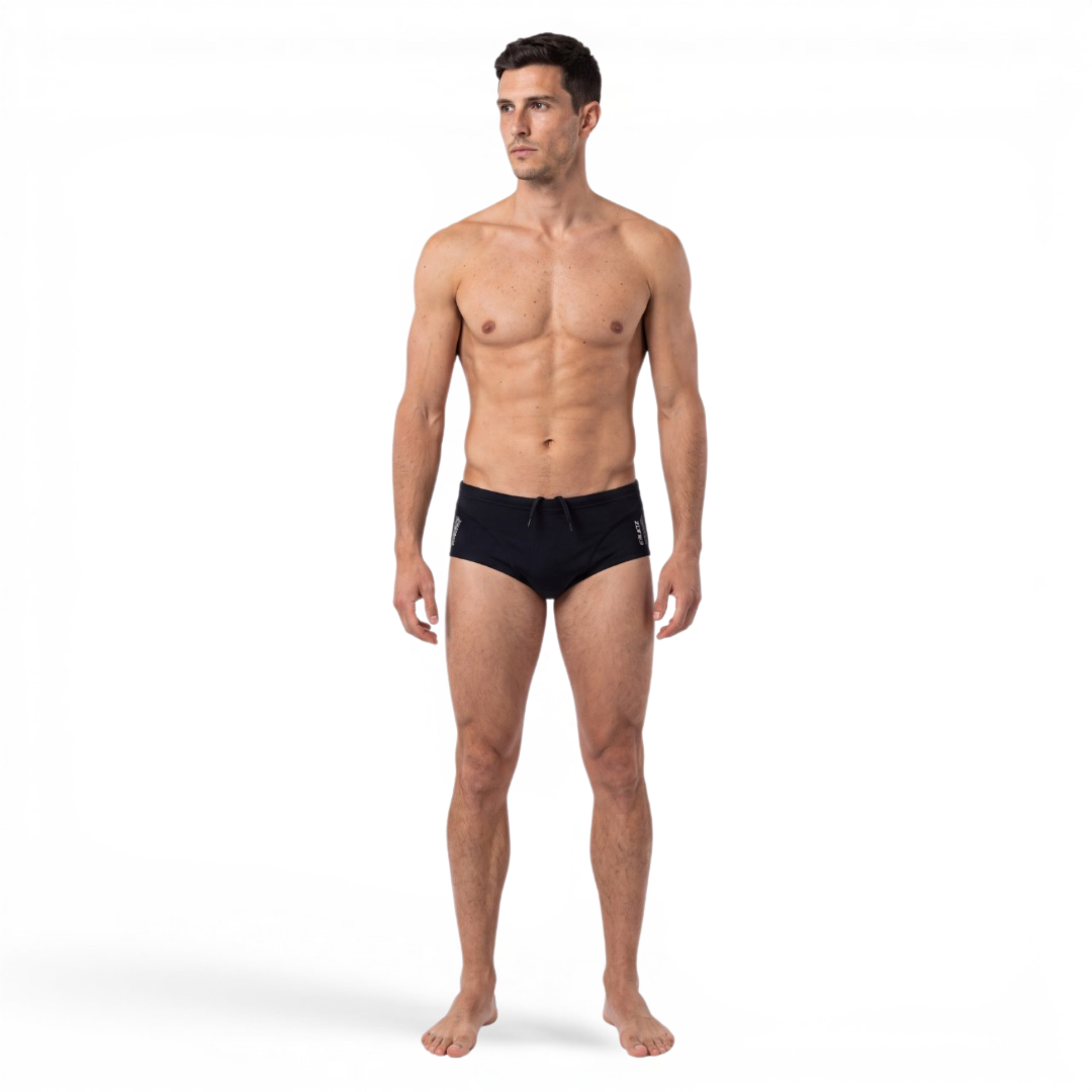 A male model standing against a white studio background, wearing black swim briefs.