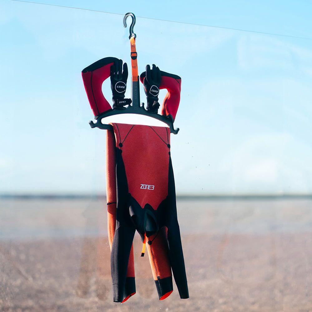 Zone3 wetsuit hung on teh Zone3 C-Monsta_Wetsuit_Hanger. blurred beach background. 