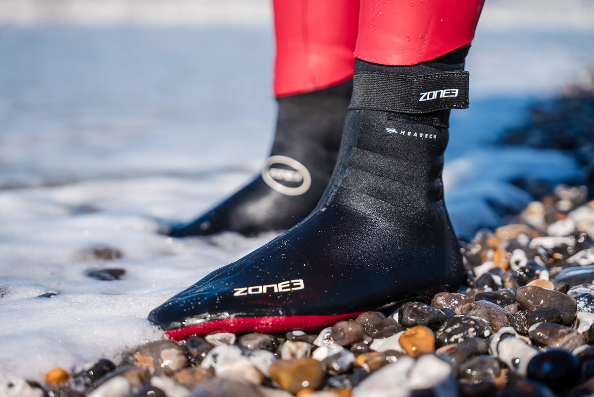 Athlete wearing the Zone3 Heat-Tech_Socks at the beach. standing on the edge on top of pebbles 