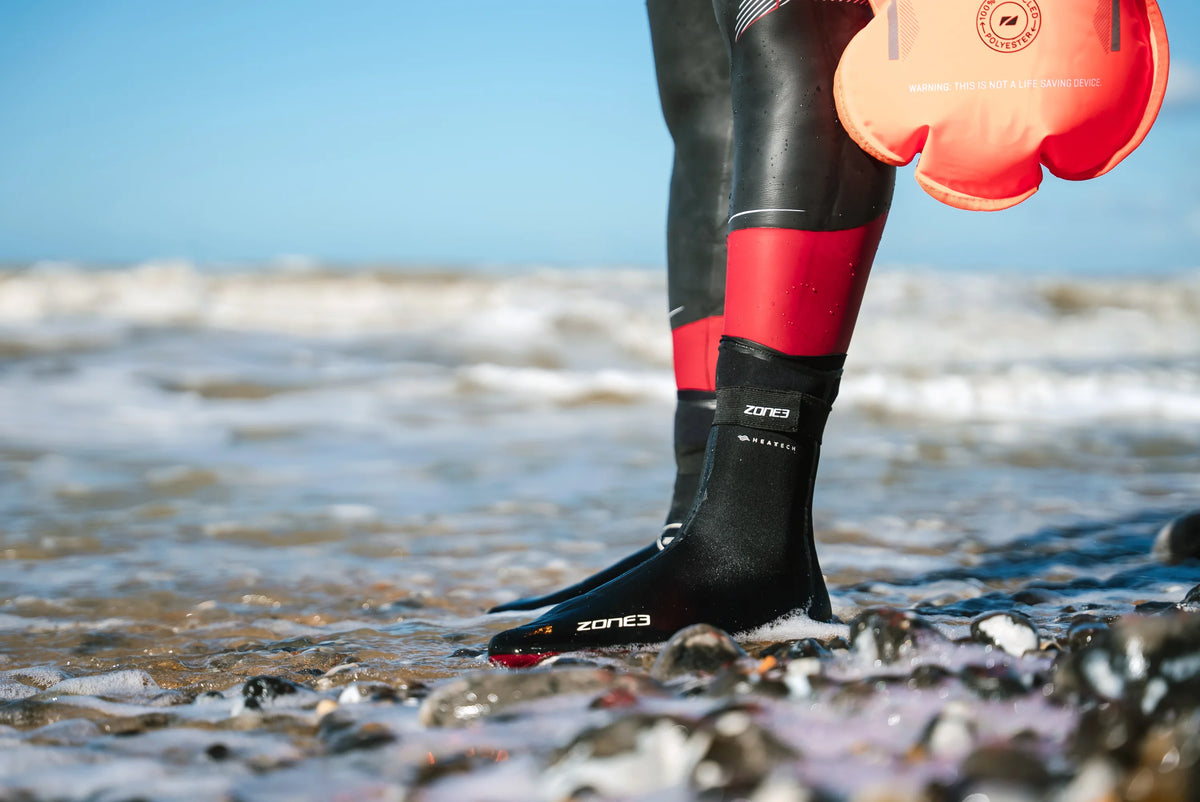 Athlete wearing the Zone3 Heat-Tech_Socks at the beach. standing on the edge on top of pebbles 