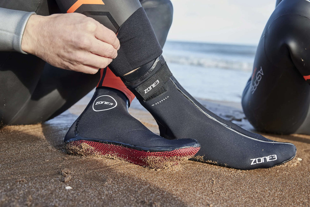 Athlete putting on the Zone3 Heat Tech socks at the beach. 