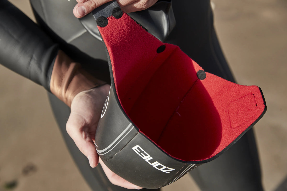 close up of an athlete holding the Heat Tech swim cap showing the red material inside the cap. 