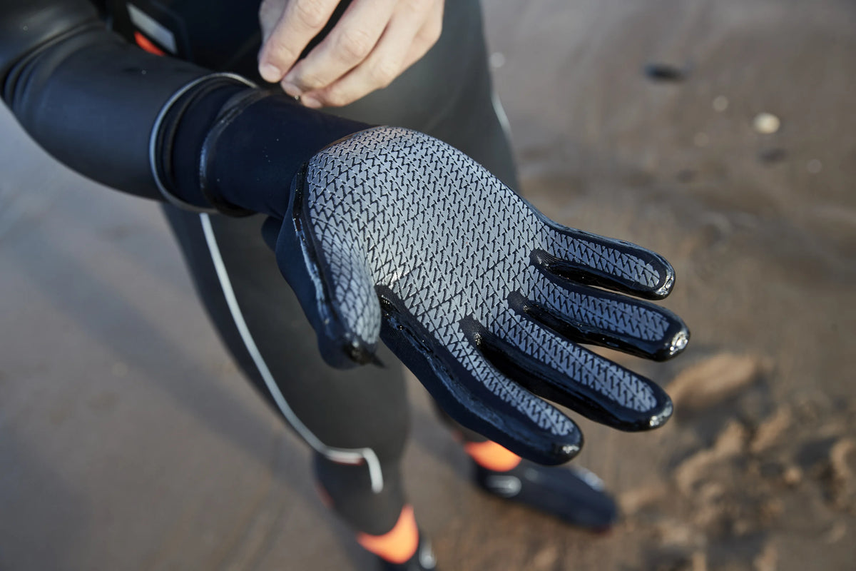 Close up of the Zone3 heat tech swim gloves at the beach. 