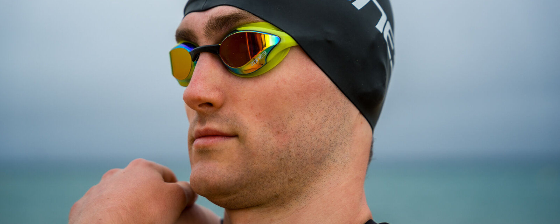 Kieran Lindars wearing Zone3 swim goggles and cap with a blue background