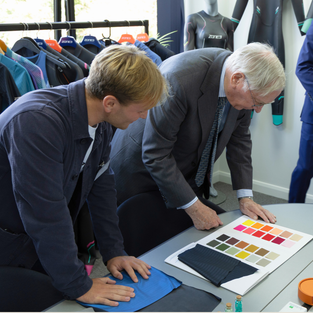 Product designer Sam showing the Duke of Gloucestershire an example colour palette used in the design process. Both are leaning over the table.
