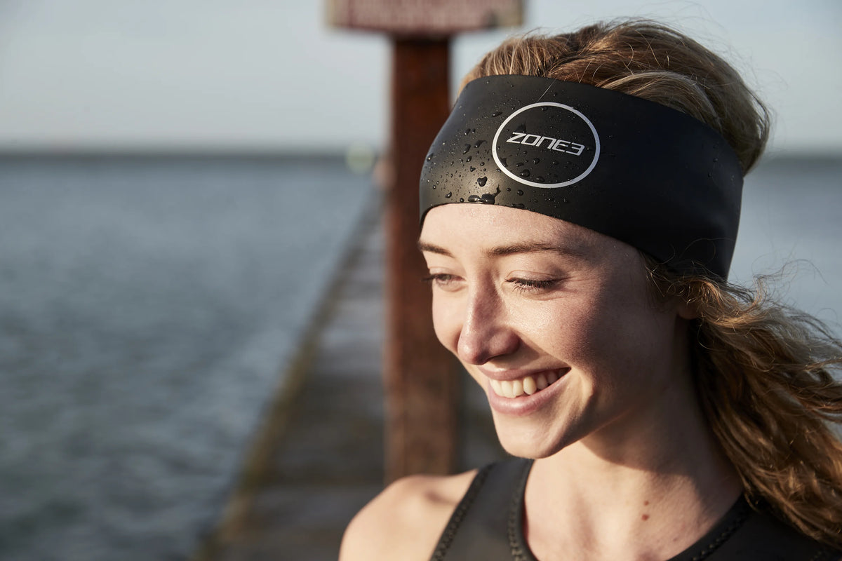 close up of a women wearing the Zone3 Neoprene Headband. blurred water background 