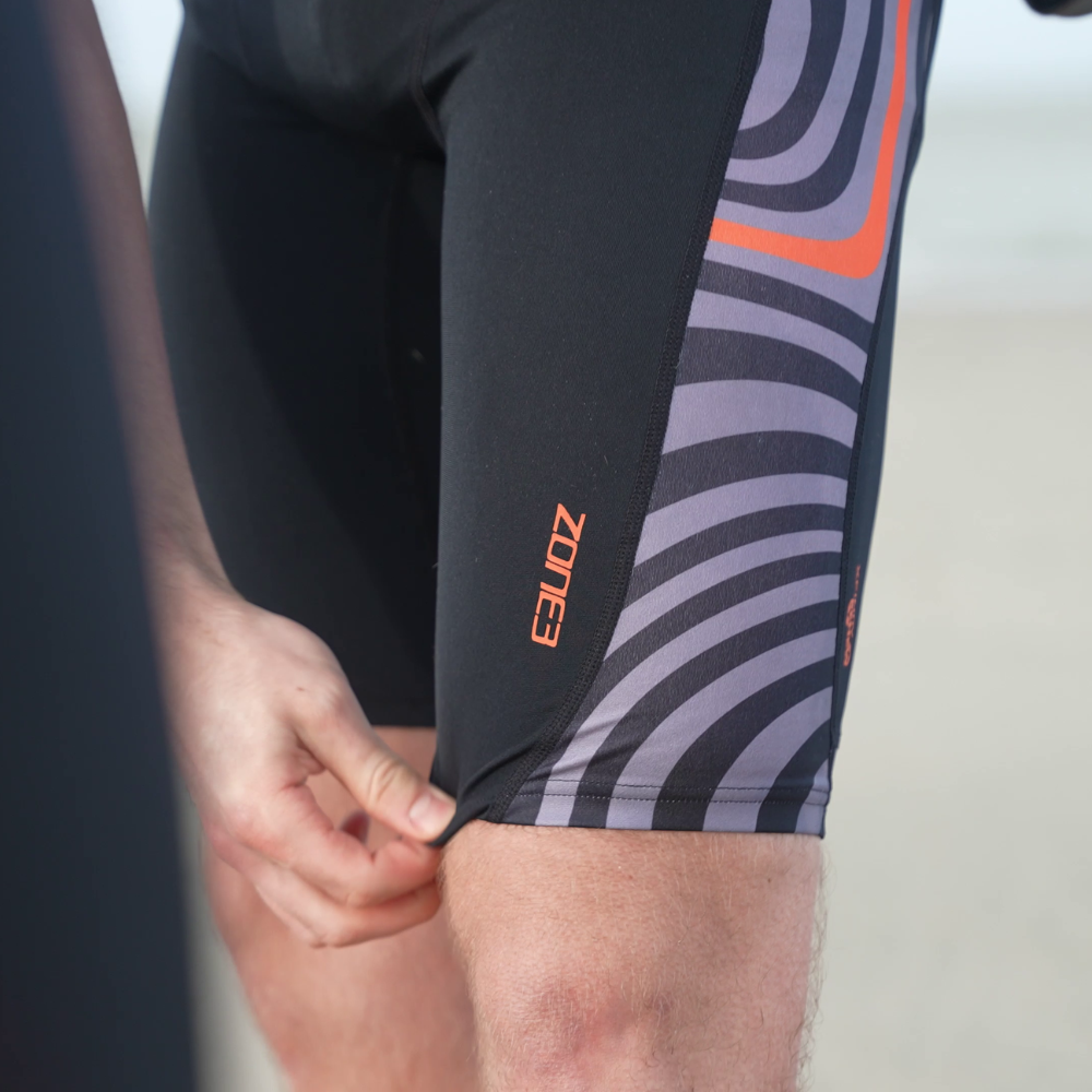 Close-up of model adjusting hem of OWS Renew Jammers, showing Zone3 logo and side panel detailing