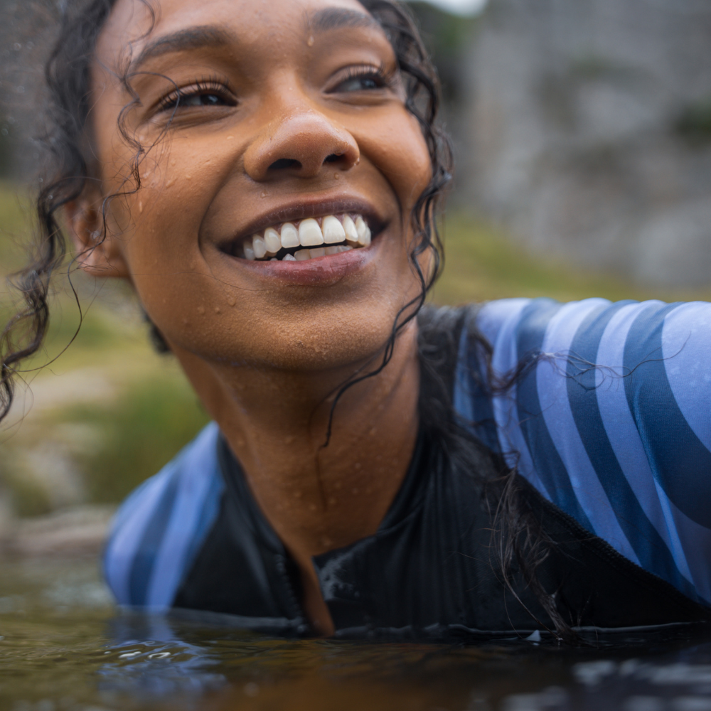 Close-up of smiling swimmer wearing long sleeve swimsuit with wet hair and striped sleeve detail