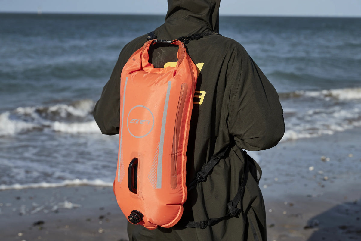 Athlete wearing the Zone3 robe and the Recycled Safety Buoy Dry Bag 28L for visibility. 