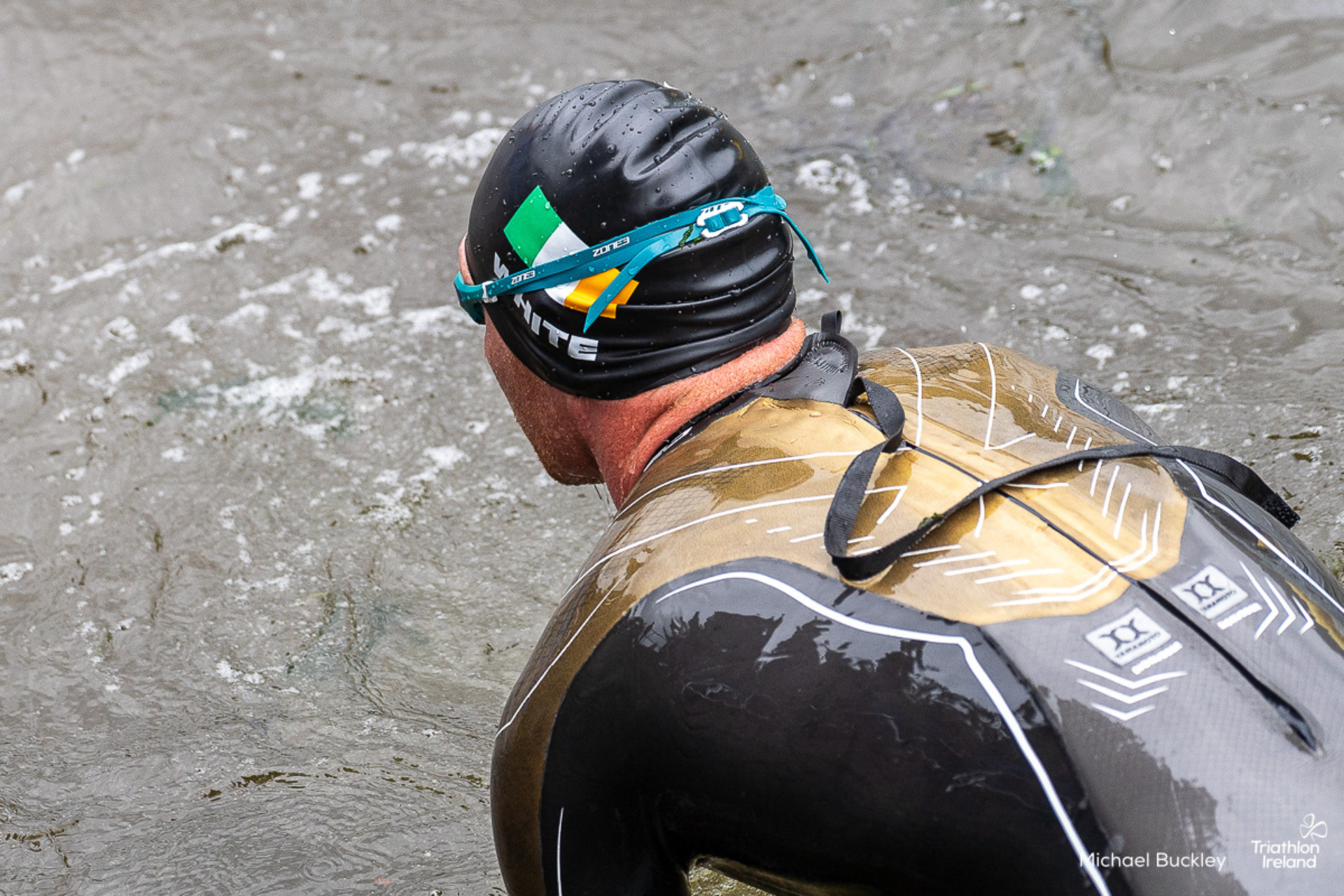 Russell White athlete wearing the Vanquish- X limited edition wetsuit in the water from the back 