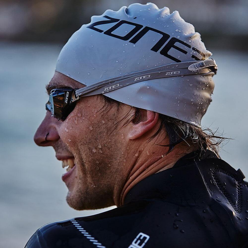 close of an Athlete wearing the Zone3 swim cap, goggles and wetsuit at the beach. 