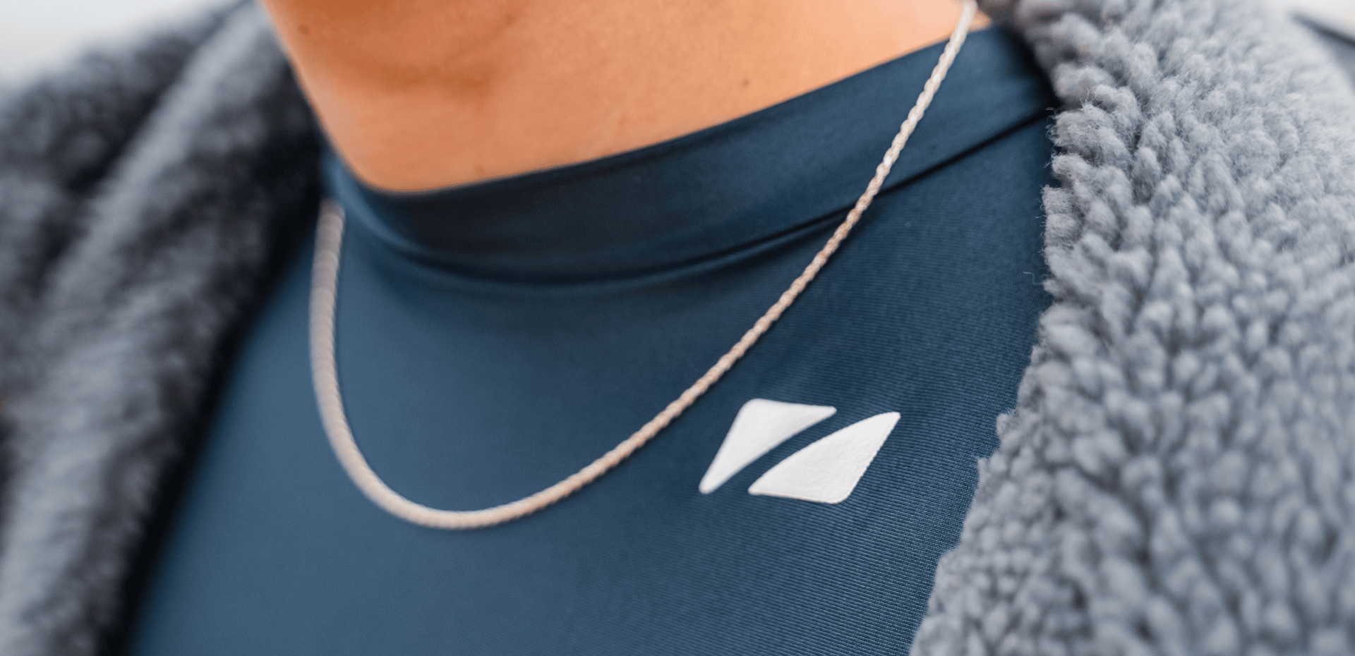 Person wearing a TI+ thermal swimsuit with a logo and a gray jacket