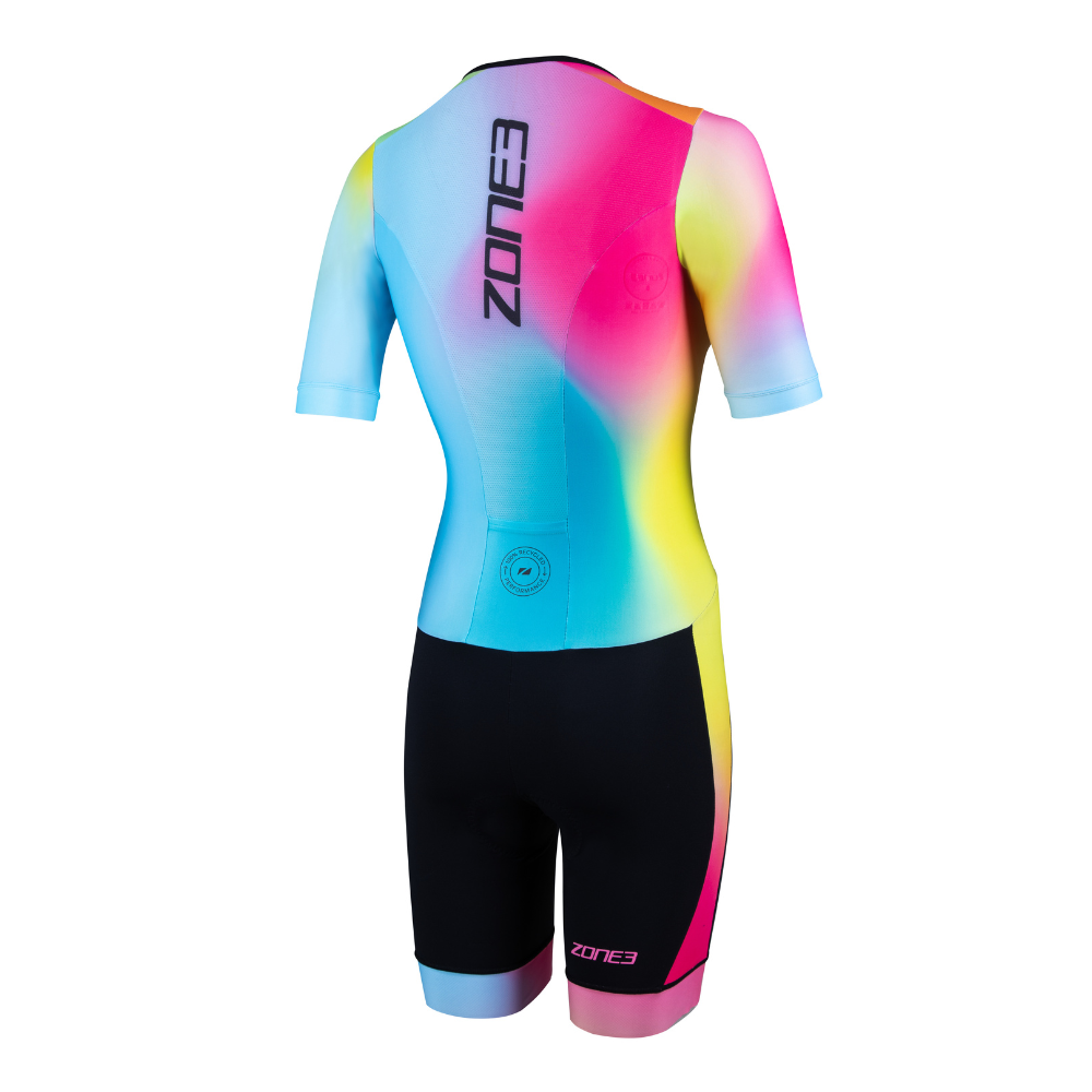 Back view of the ZONE3 Activate+ women’s short sleeve trisuit with a vertical ZONE3 logo and colourful gradient across the upper body. Shorts are black with a small circular recycled label at the lower back.