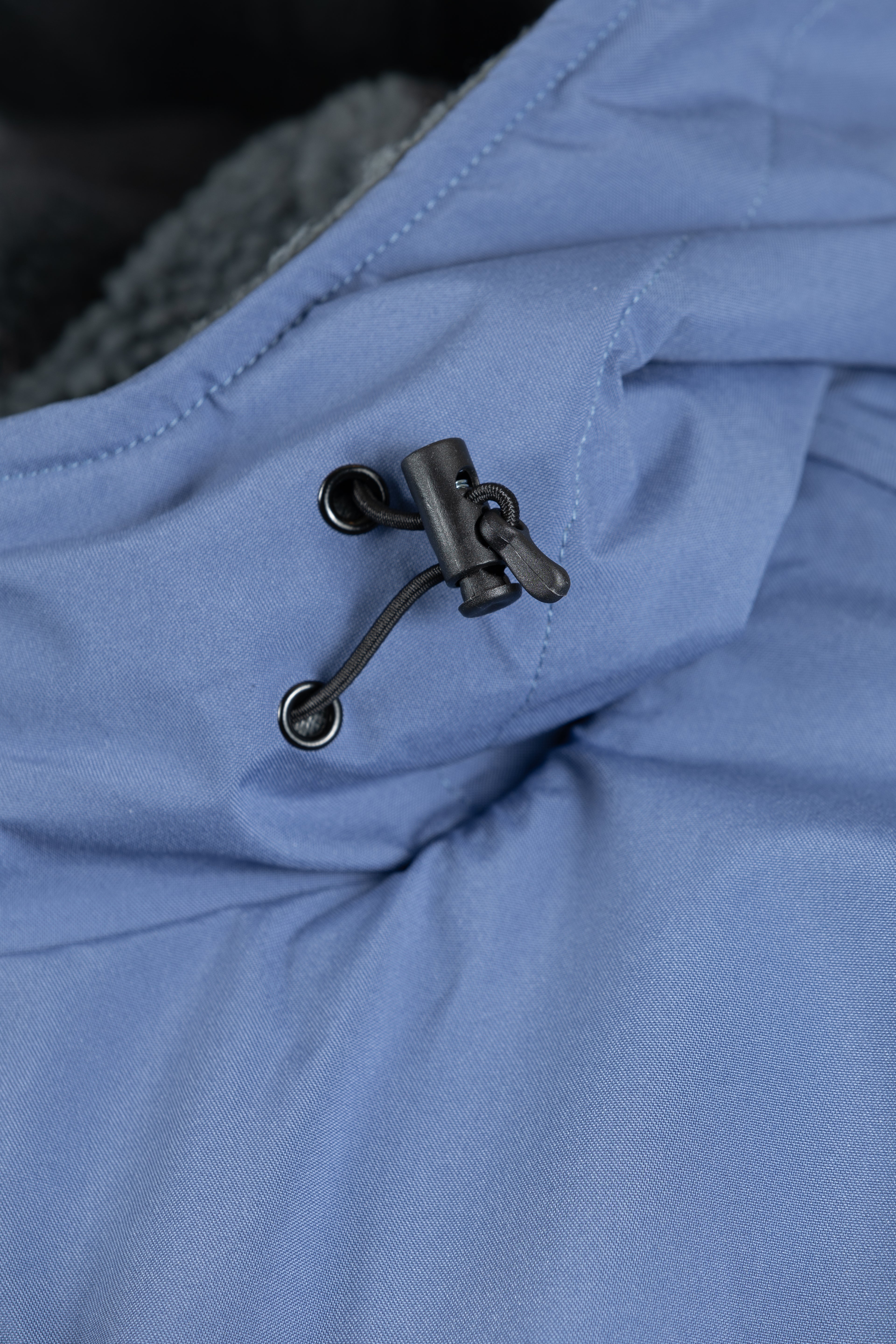Detail of the adjustable hood drawcord and toggle on the Arctic blue fabric.