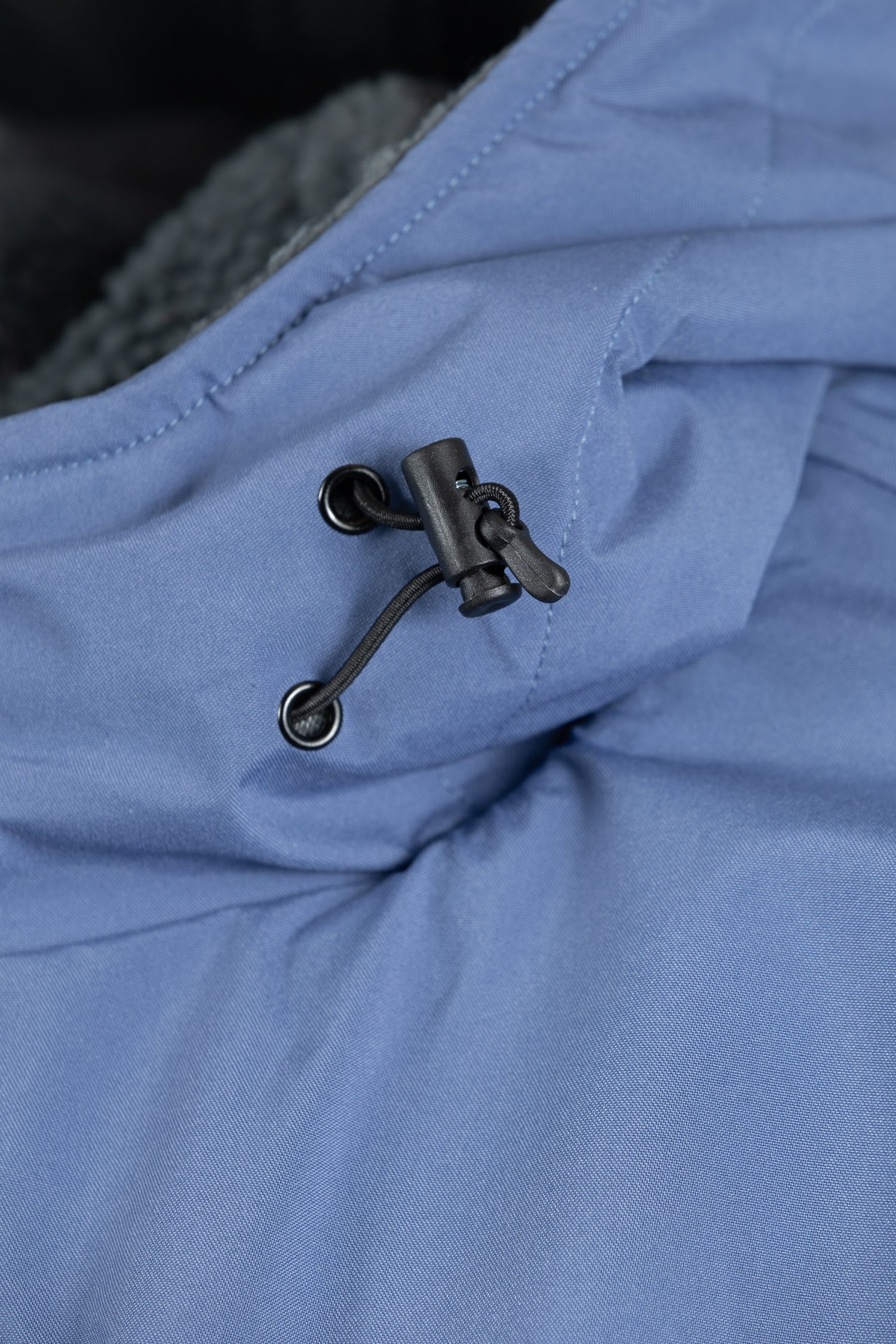 Detail of the adjustable hood drawcord and toggle on the Arctic blue fabric.