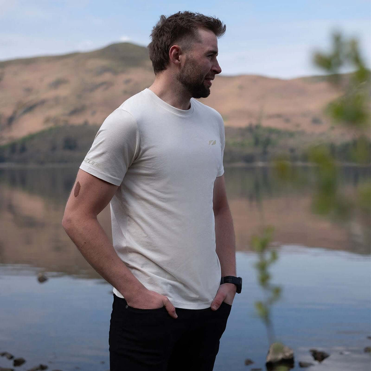 A man standing by a lake wearing a Zone3 Thirlmere Short Sleeve_T-Shirt 