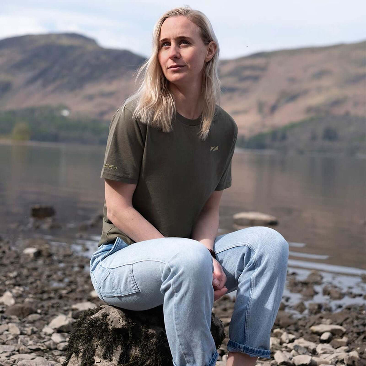 A Women sitting ona rock by a lake wearing a Zone3 Thirlmere Short Sleeve-Shirt in Khaki.